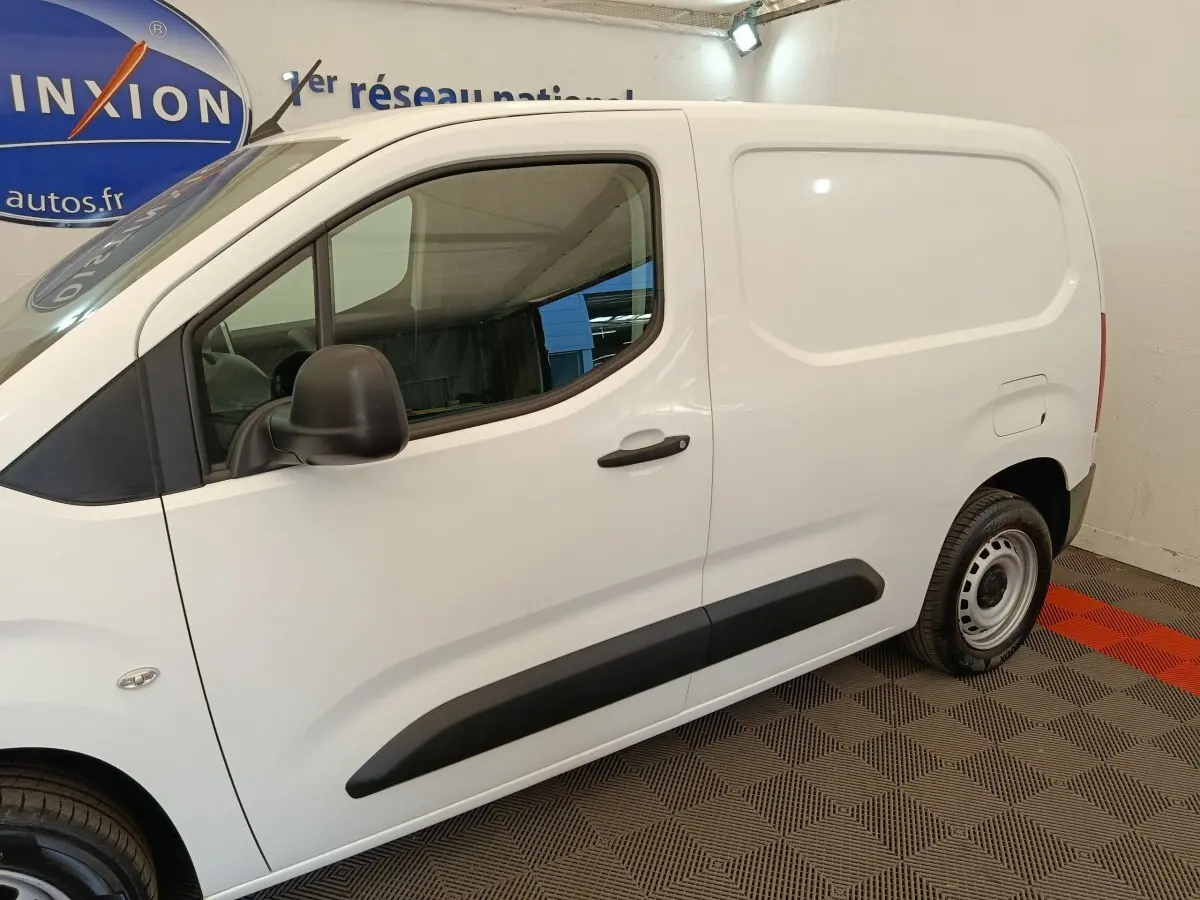 Vue de profil côté gauche d'un utilitaire Citroën Berlingo blanc avec protections latérales noires et jantes acier.