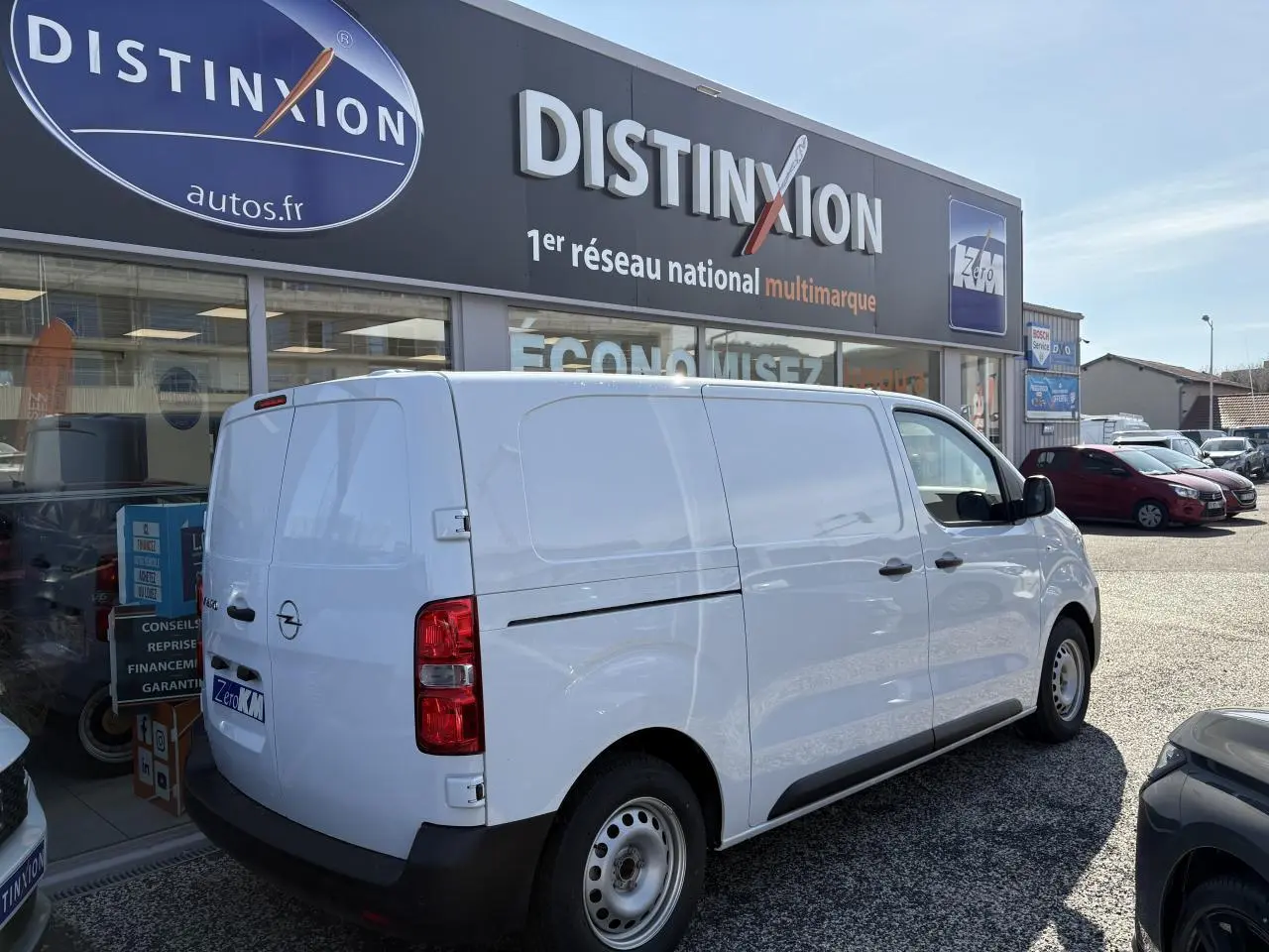 Vue 3/4 arrière droite d’un utilitaire Opel Vivaro blanc stationné devant un concessionnaire.