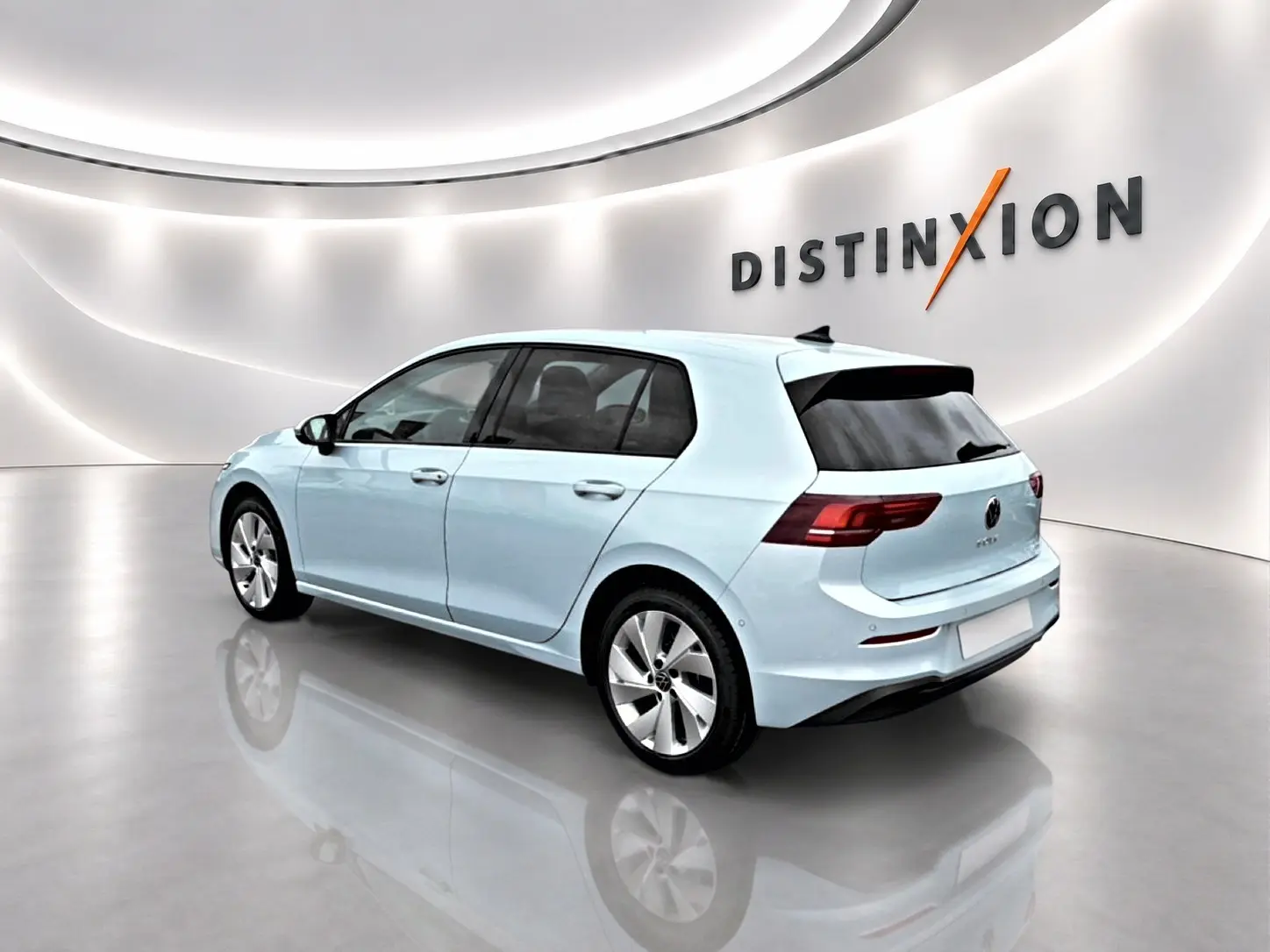 Volkswagen Golf bleu glacier vue 3/4 arrière droit dans un showroom lumineux avec logo Distinxion en arrière-plan.