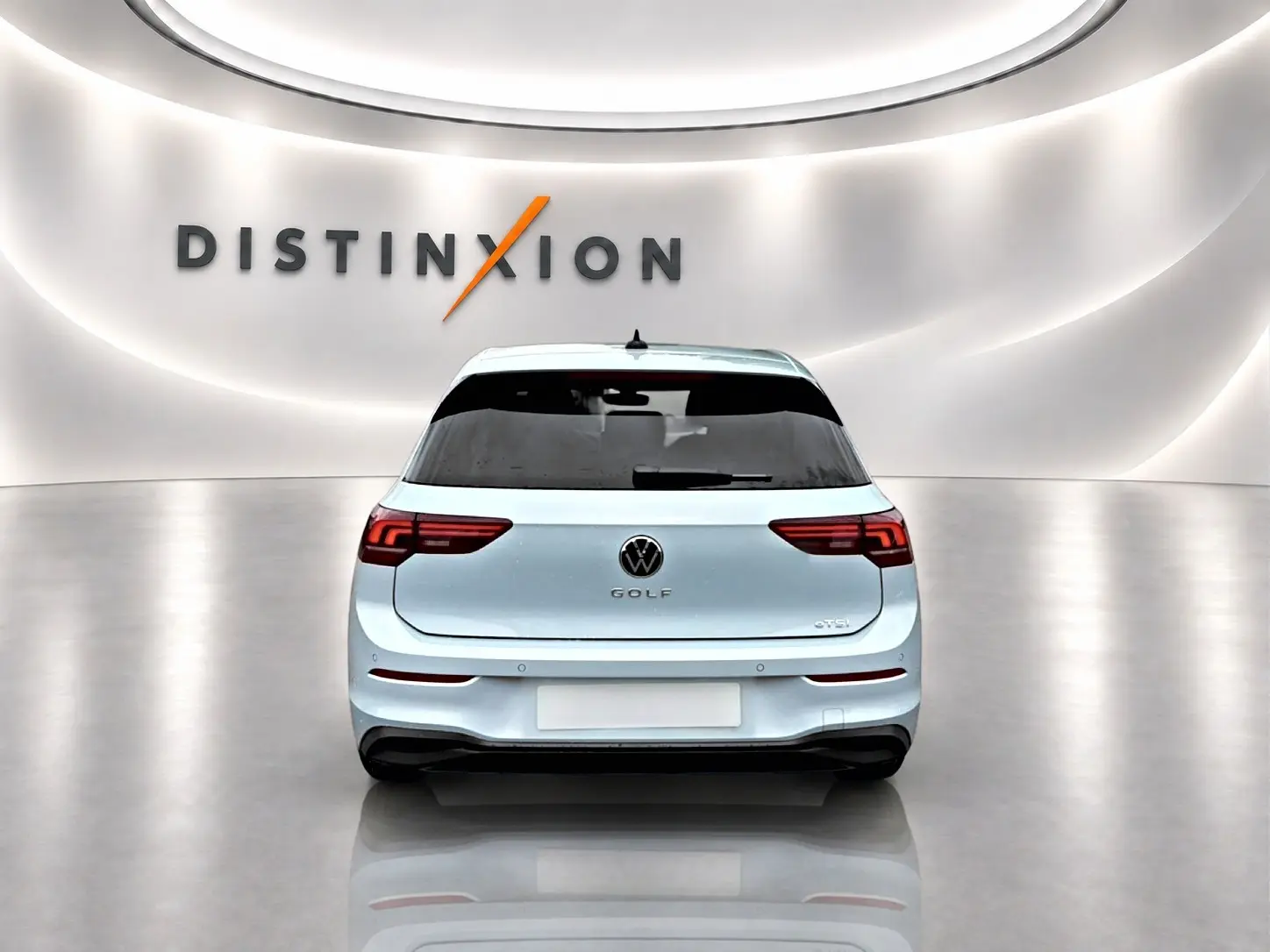Vue arrière d'une Volkswagen Golf 1.5 etsi evo2 bleu glacier dans un showroom lumineux avec logo Distinxion en arrière-plan.