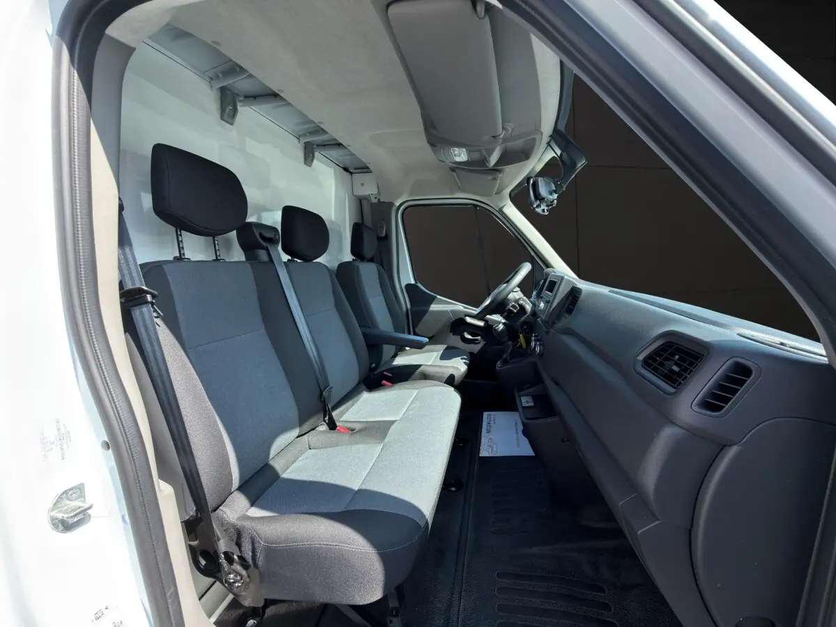 Intérieur du Renault Master 2024 vu côté conducteur, montrant les sièges gris et le tableau de bord noir.