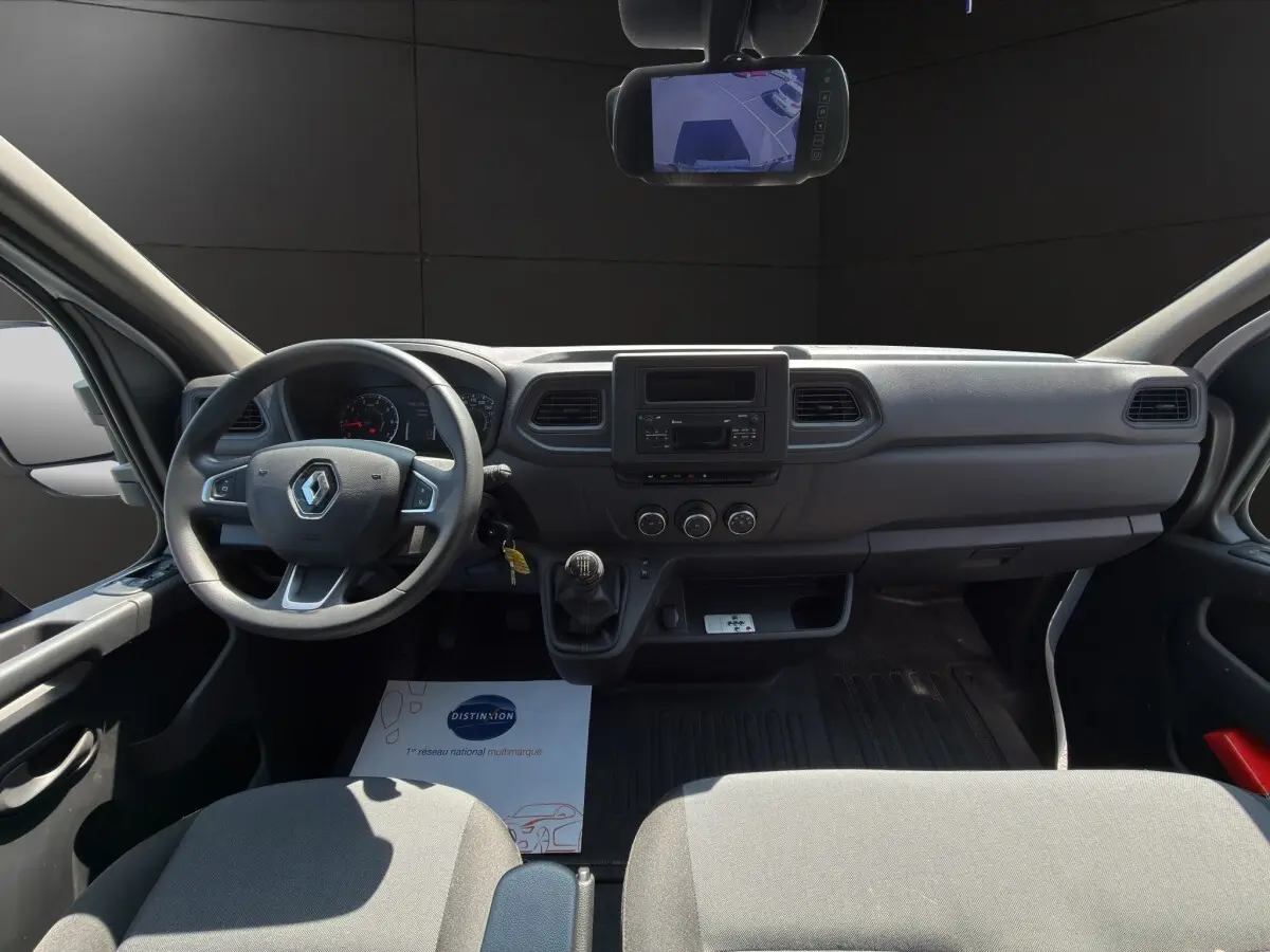 Vue intérieure avant du Renault Master 2024 blanc, tableau de bord simple avec volant, boîte manuelle et écran central.