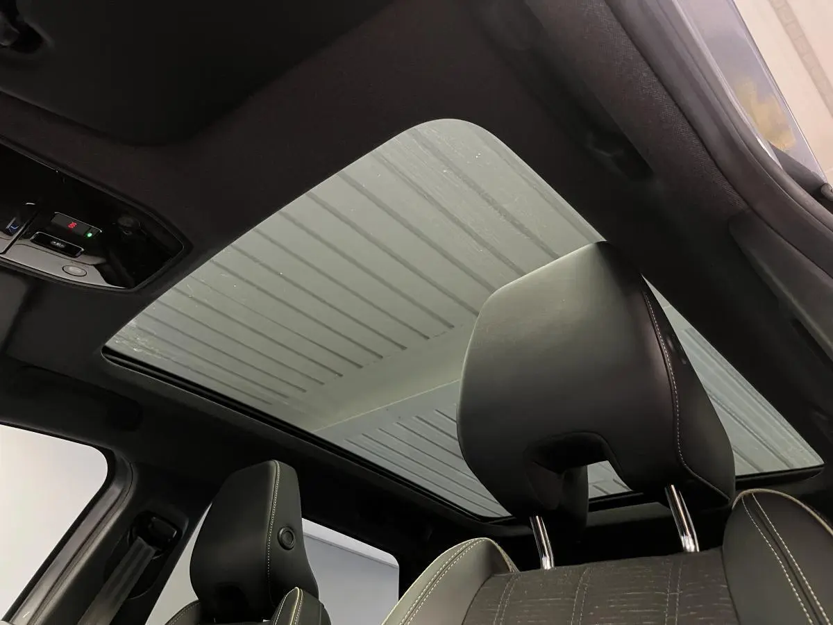 Vue intérieure du toit panoramique fixe et des appuie-têtes noirs avec surpiqûres claires du Renault Austral gris.