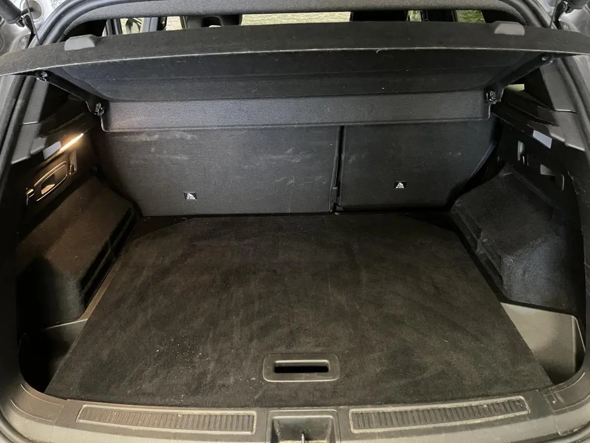 Coffre ouvert vu de l'arrière d'un Renault Austral gris, avec plancher plat et habillage intérieur noir.