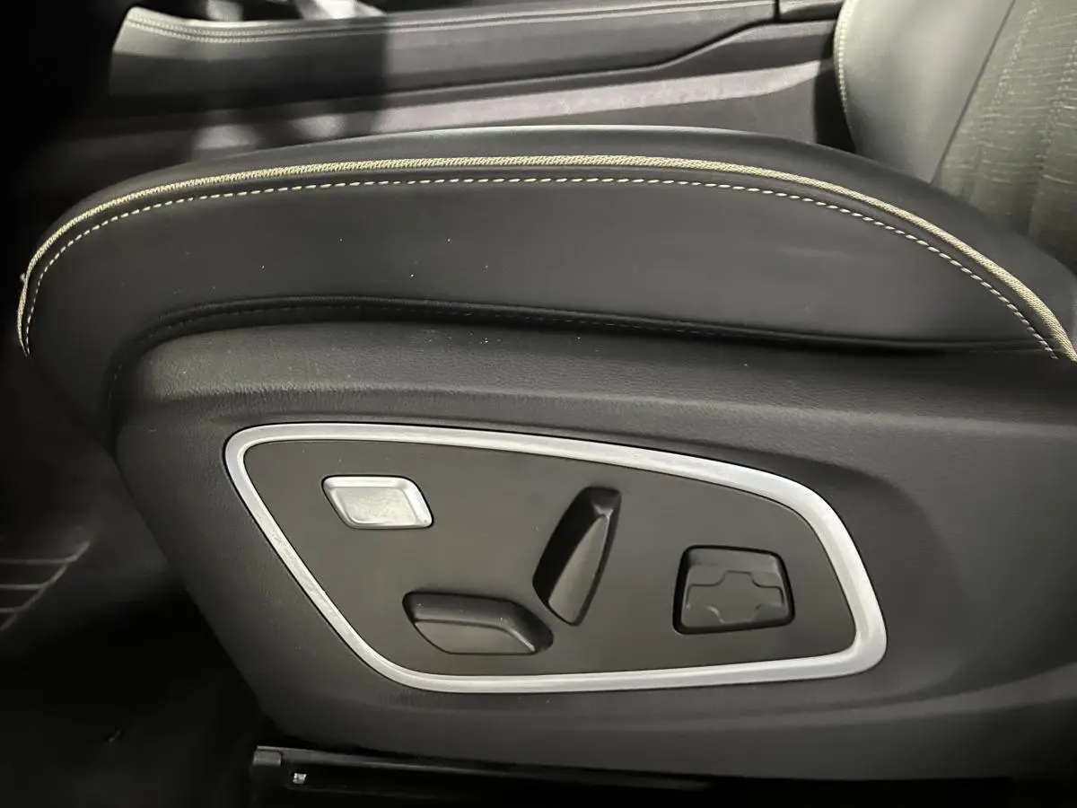 Gros plan sur les commandes électriques du siège conducteur noir avec surpiqûres beiges du Renault Austral 2024.