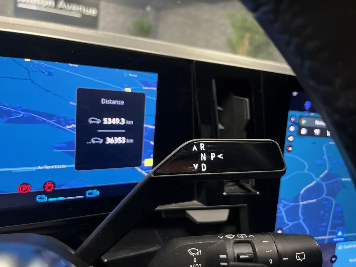 Le levier de boîte automatique noir de la Renault Austral 2024, avec affichage des modes de conduite sur fond d'écran de navigation.