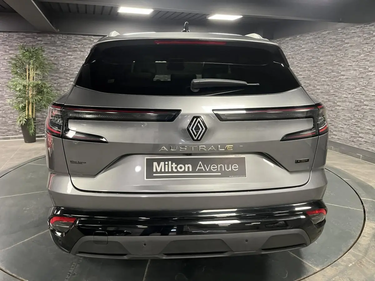 Vue arrière du Renault Austral gris avec feux LED horizontaux et logo central dans un showroom intérieur.