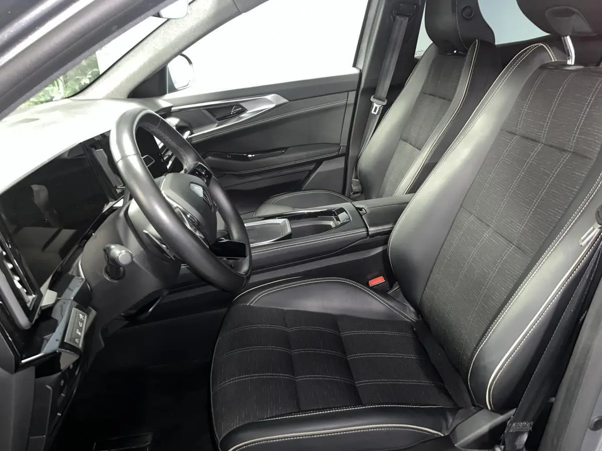 Vue intérieure côté conducteur du Renault Austral 2024, sièges en similicuir et tissu carbone foncé avec surpiqûres or.