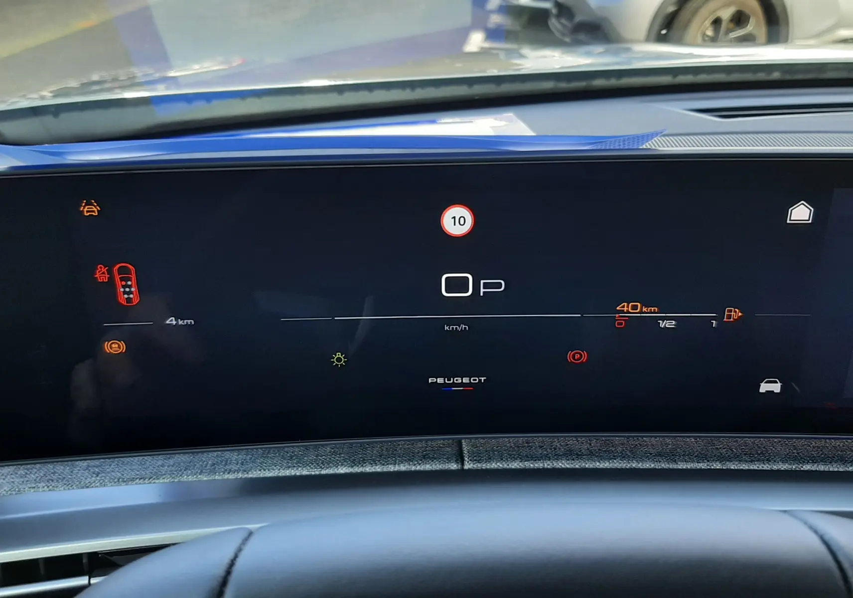 Tableau de bord numérique du Peugeot 5008 bleu Ingaro, affichant la vitesse et alertes, vue depuis le poste de conduite.