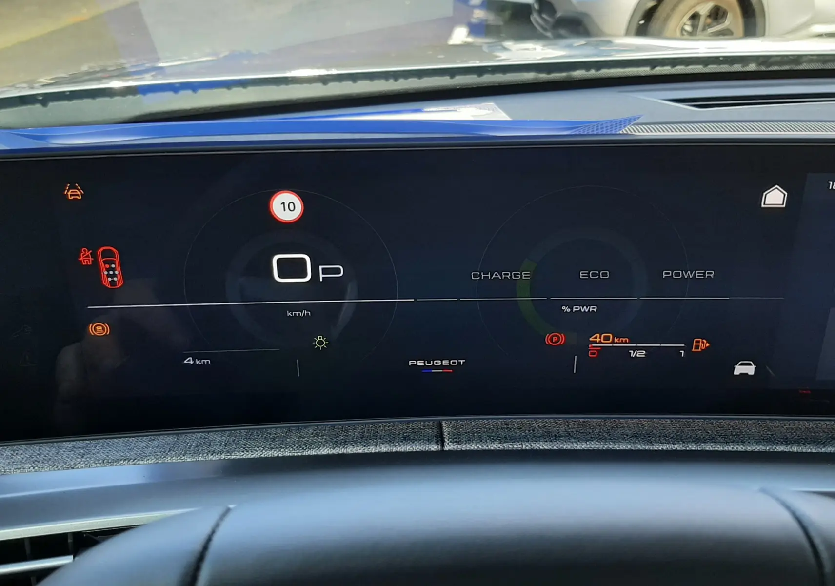 Vue du tableau de bord numérique du Peugeot 5008 bleu Ingaro 2025, affichant les indicateurs de vitesse et d'énergie hybride.