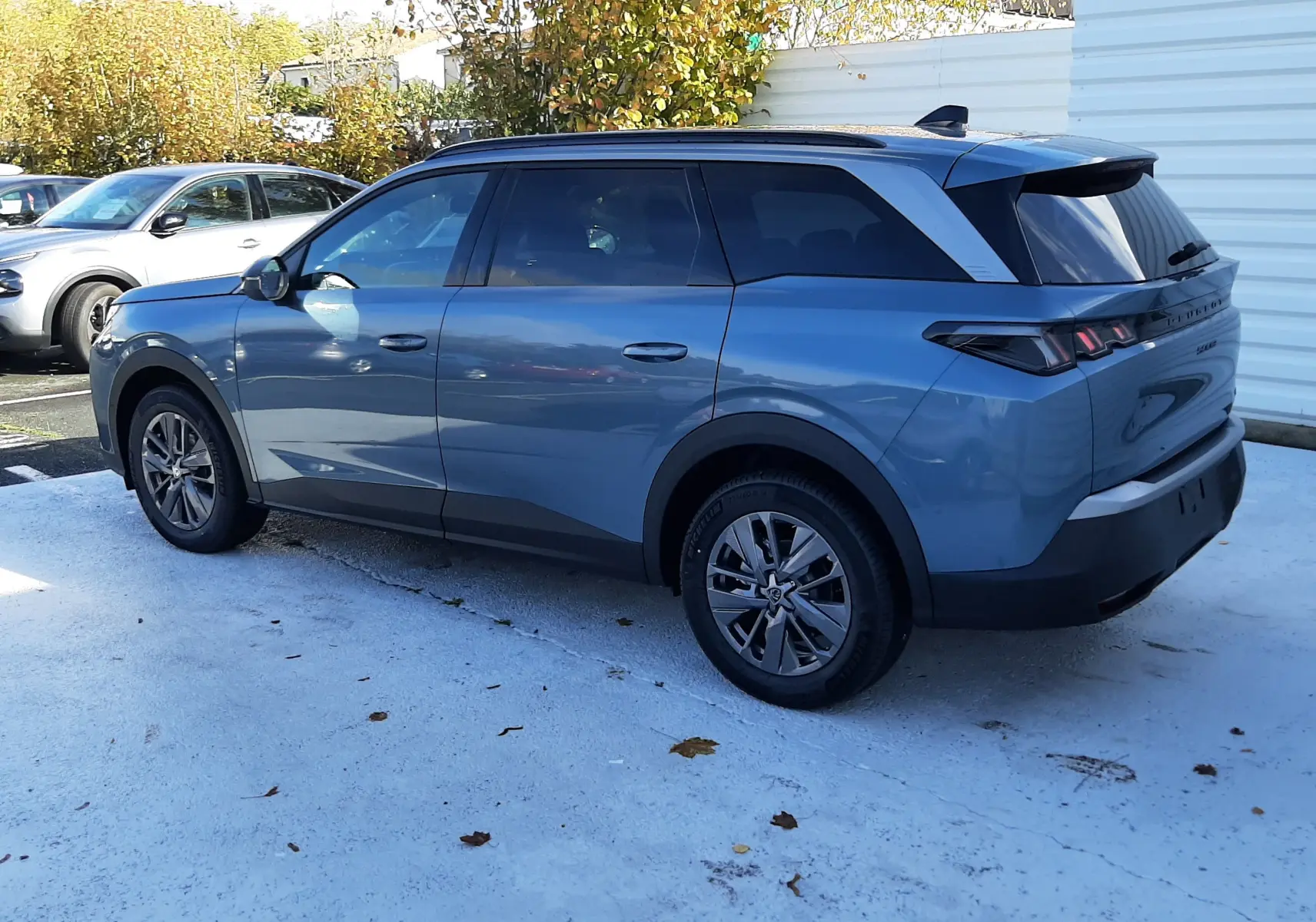 Peugeot 5008 bleu Ingaro en vue 3/4 arrière droit, avec toit noir et vitres teintées sur parking extérieur.