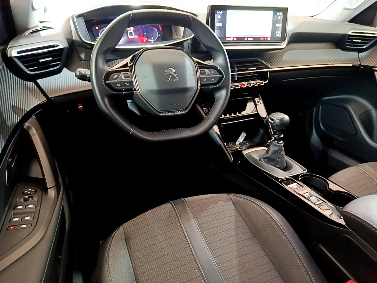 Vue intérieure avant du Peugeot 2008 noir 2021, volant cuir multifonctions, écran tactile 10 pouces et boîte manuelle.