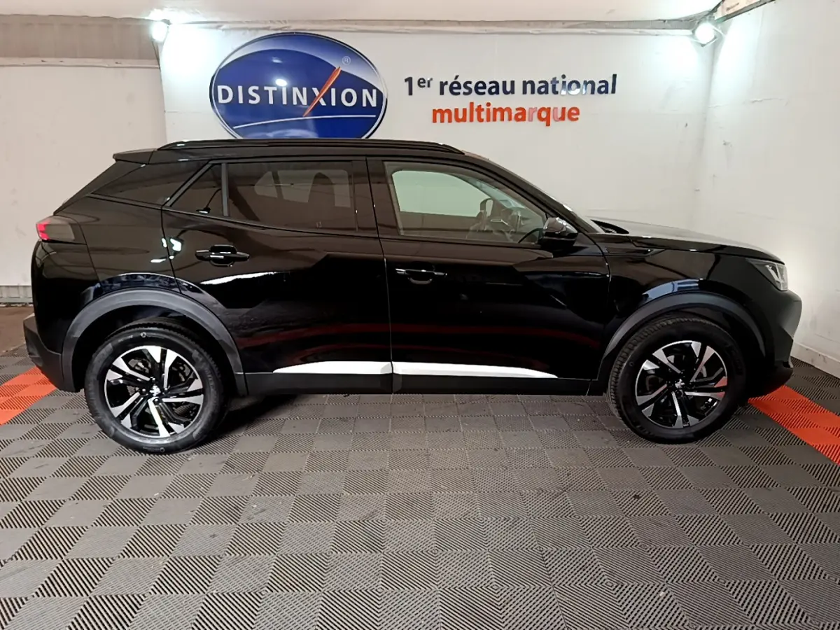 Profil côté gauche d'un Peugeot 2008 noir 2021 dans un showroom avec jantes bicolores et toit noir.