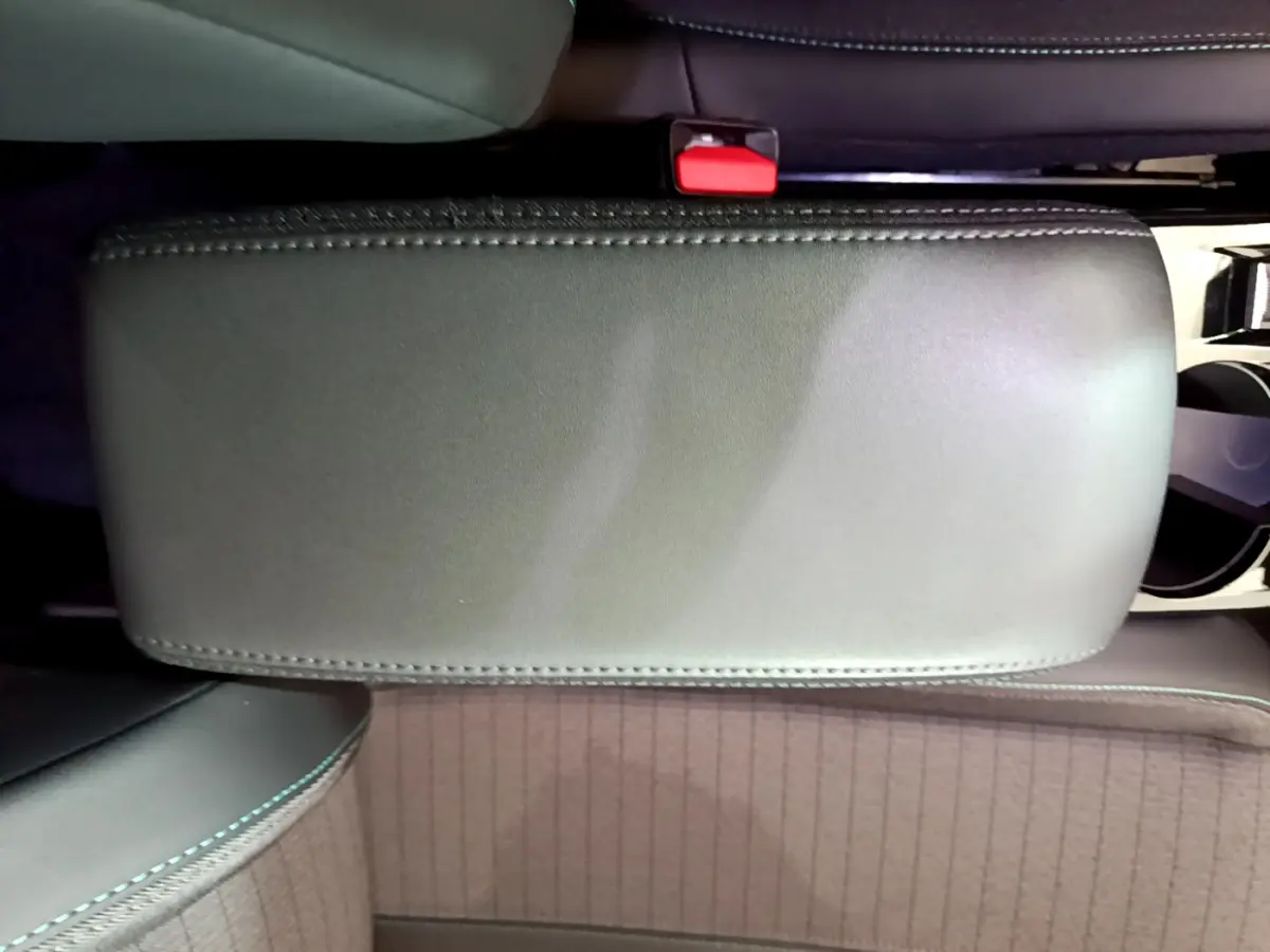 Vue plongeante sur l'accoudoir central noir et les sièges avant en tissu gris du Peugeot 2008 PureTech 130 S&S Allure Business.