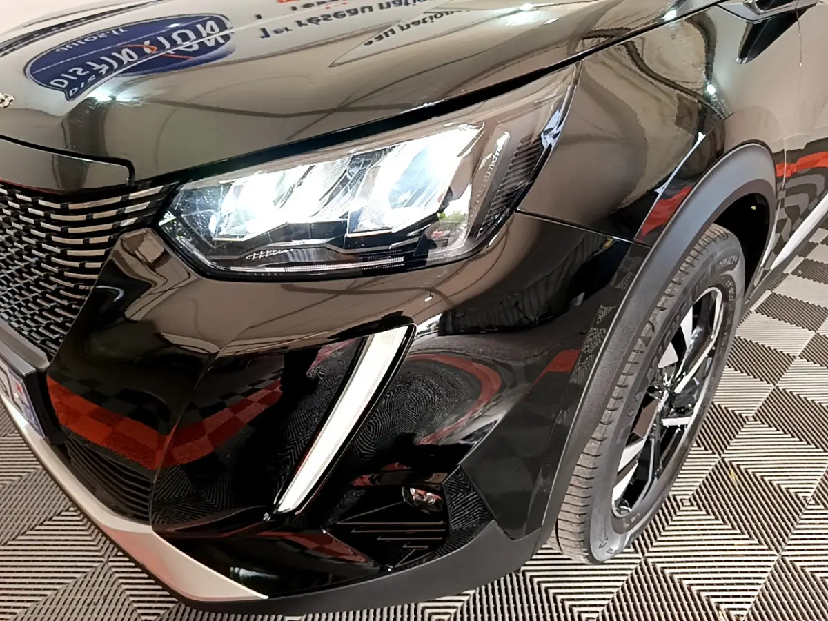 Gros plan sur l'avant droit noir brillant du Peugeot 2008 avec phares LED et jante alliage visible.