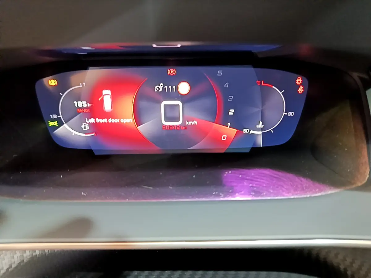 Gros plan sur le tableau de bord numérique du Peugeot 2008 2021, affichant vitesse, jauge et alertes en rouge et blanc.