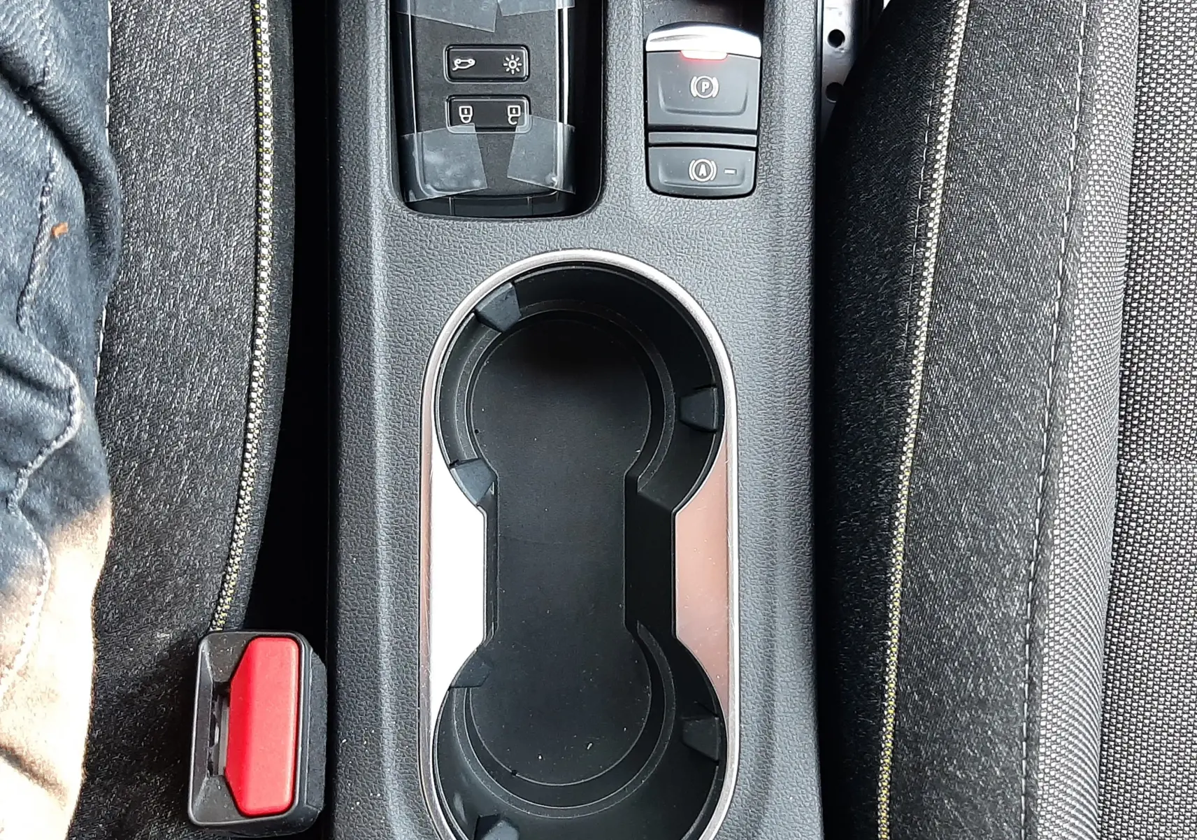 Vue plongeante sur la console centrale du Renault Captur gris Cassiopée, avec porte-gobelets et boutons de frein à main électronique.