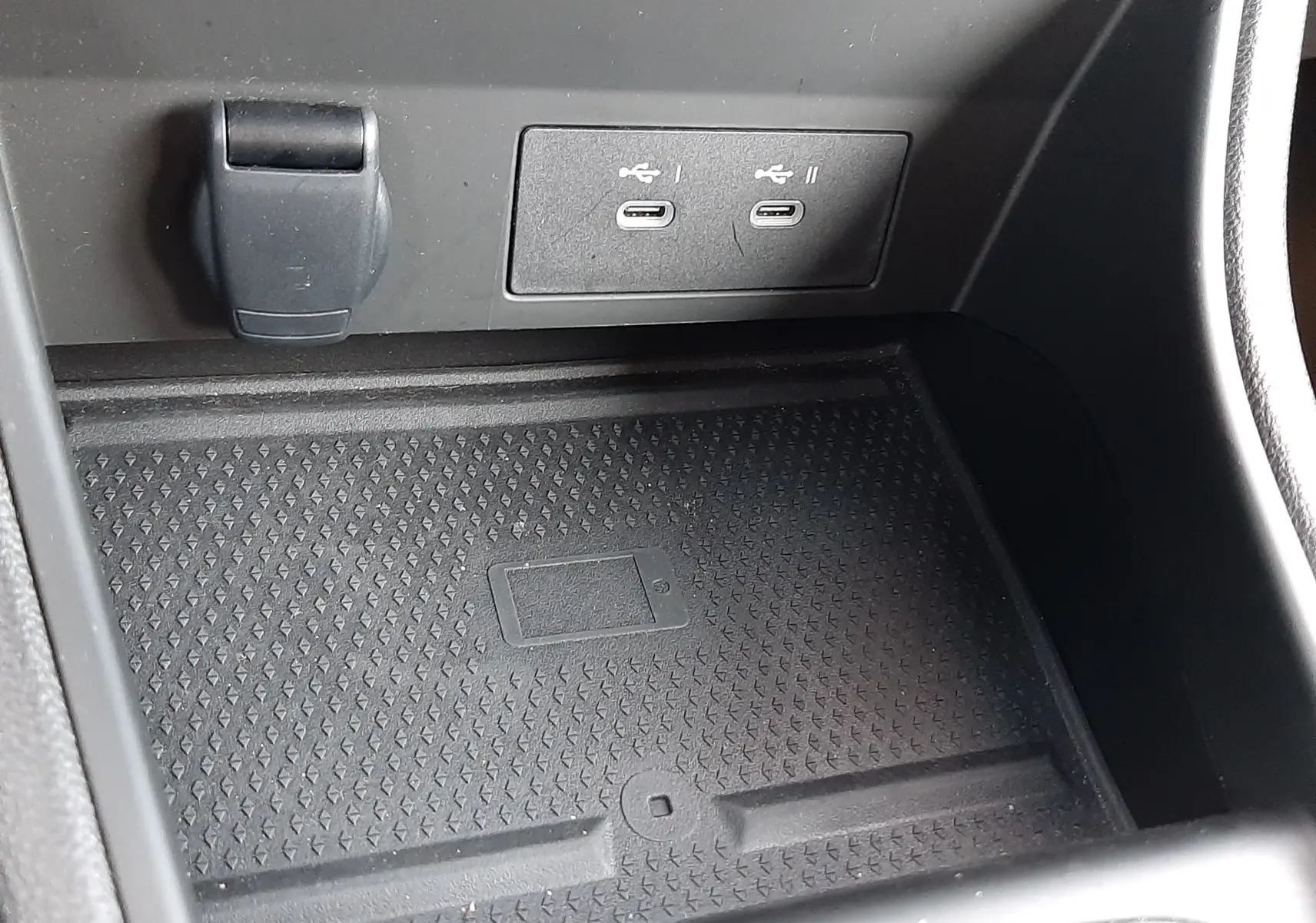 Gros plan sur la console centrale du Renault Captur gris Cassiopée 2025, montrant les ports USB-C et un espace de rangement avec chargeur sans fil.