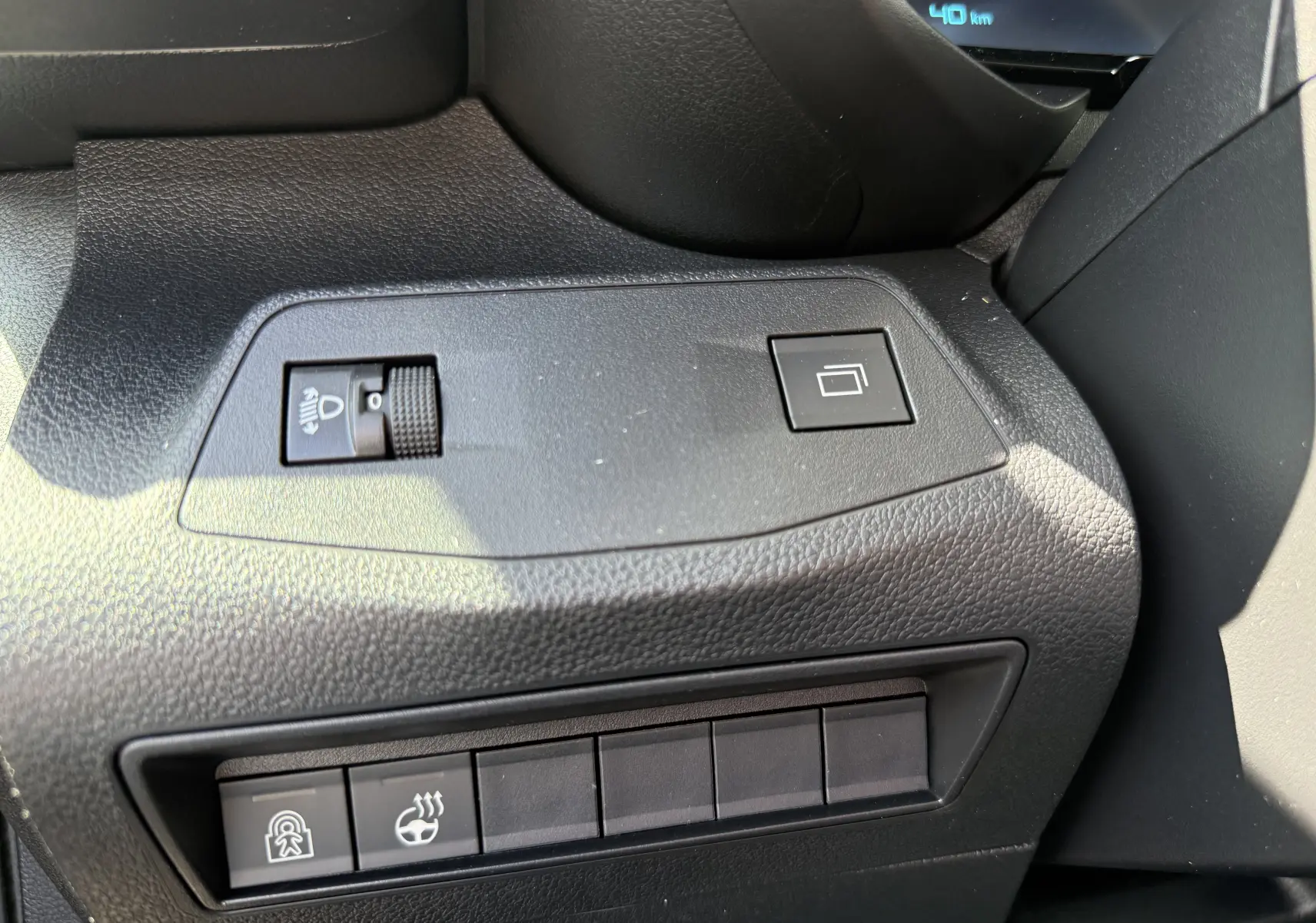 Vue rapprochée du tableau de bord côté gauche du Citroën Berlingo gris, avec commandes de réglage des phares et boutons fonctionnels.