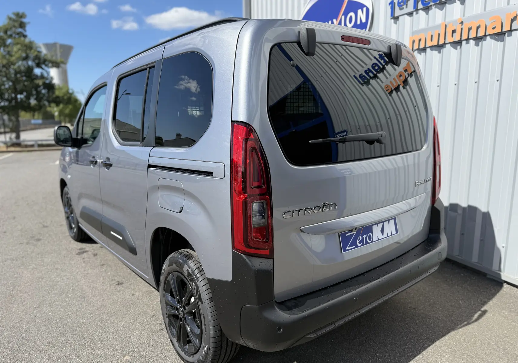 Vue 3/4 arrière droite d'un Citroën Berlingo gris Artense métallisé avec vitres teintées et jantes noires.