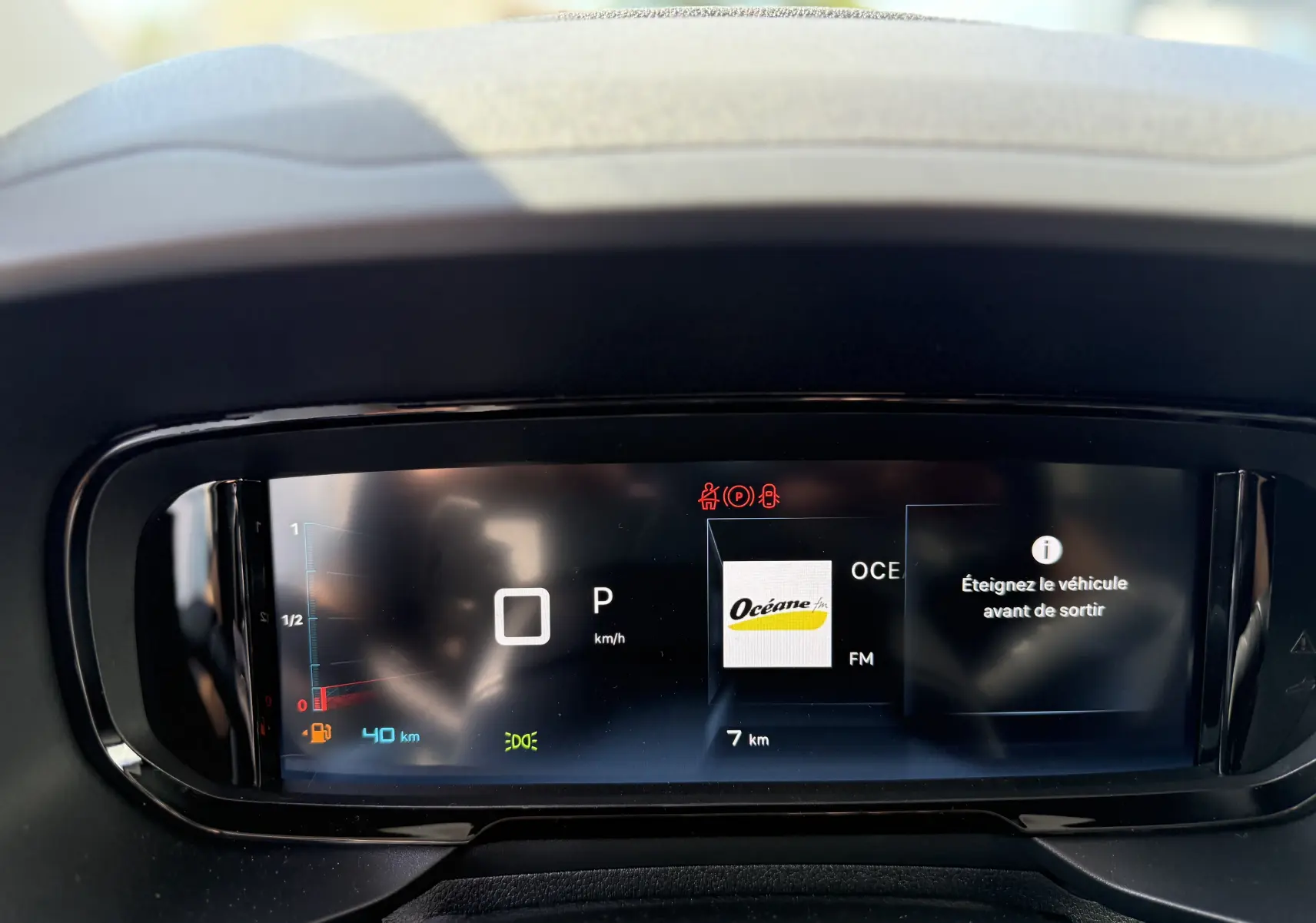 Tableau de bord numérique du Citroën Berlingo 2026 gris, affichant la vitesse, radio et message d’alerte.