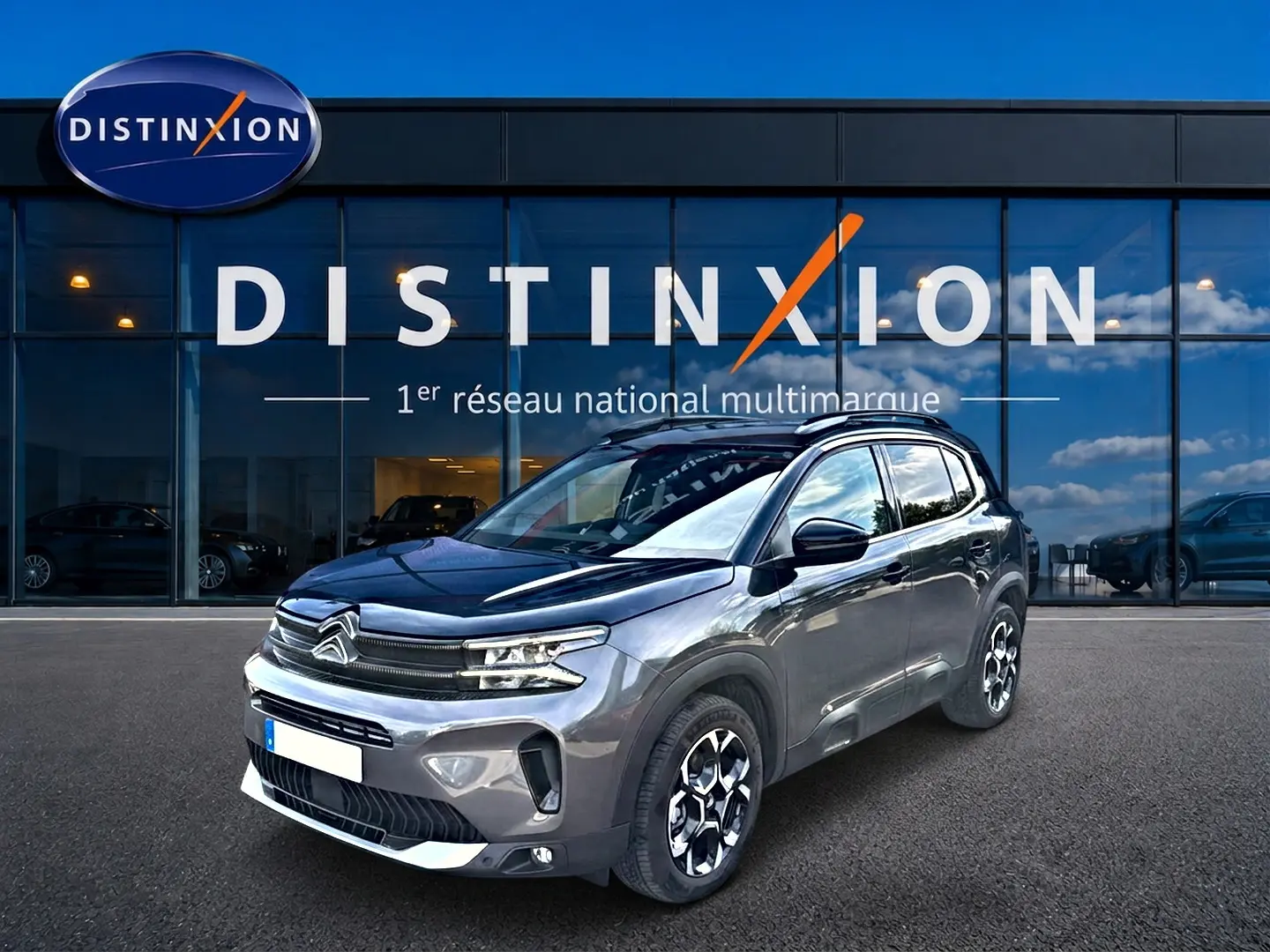Citroën C5 Aircross gris en 3/4 avant droit, avec jantes alu et toit noir brillant devant showroom Distinxion.