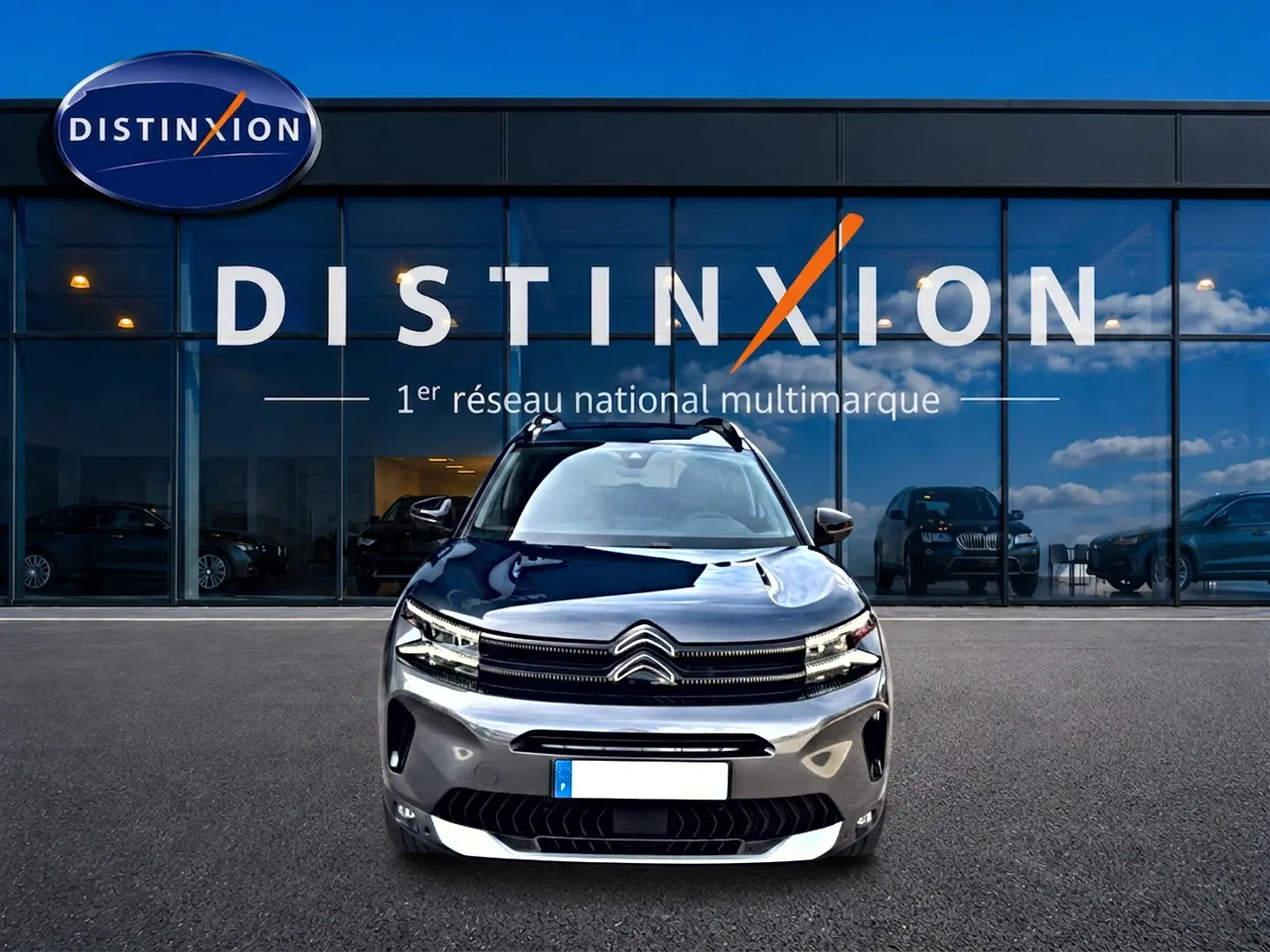 Vue frontale d'un Citroën C5 Aircross gris 2025 avec calandre distinctive et phares LED devant un showroom Distinxion.