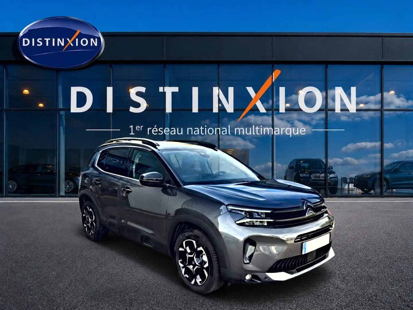 Citroën C5 Aircross gris 3/4 avant droit avec jantes alu et barres de toit devant vitrine Distinxion.