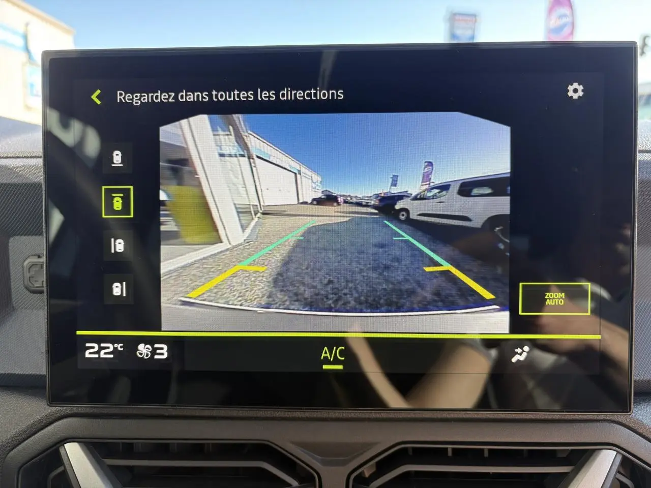 Écran central montrant la caméra de recul du Dacia Duster blanc métallisé, vue arrière avec lignes de guidage.