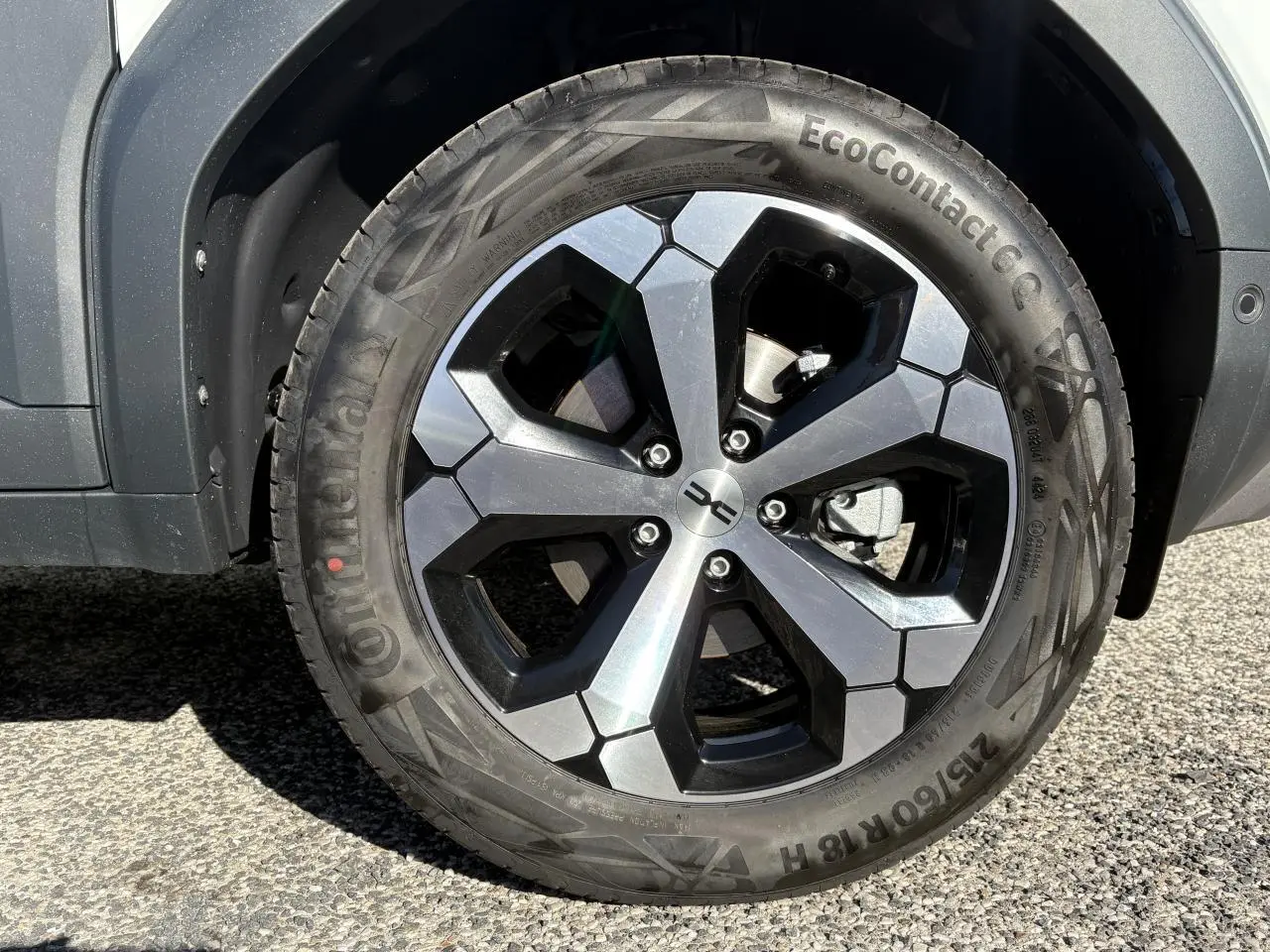 Gros plan sur la jante alliage 18 pouces noire et argent du Dacia Duster blanc métallisé, côté droit arrière.