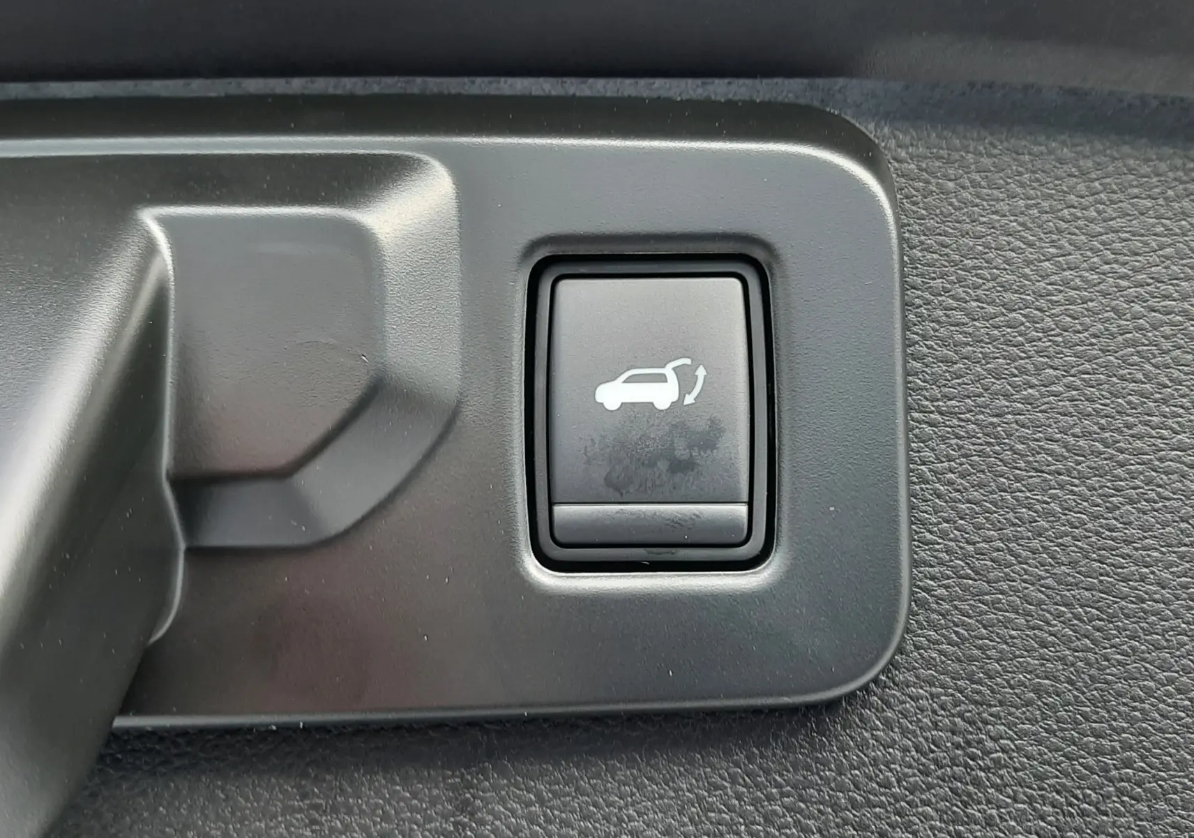 Bouton intérieur noir avec pictogramme d'ouverture de hayon sur Renault Symbioz E-Tech Full Hybrid 2025.