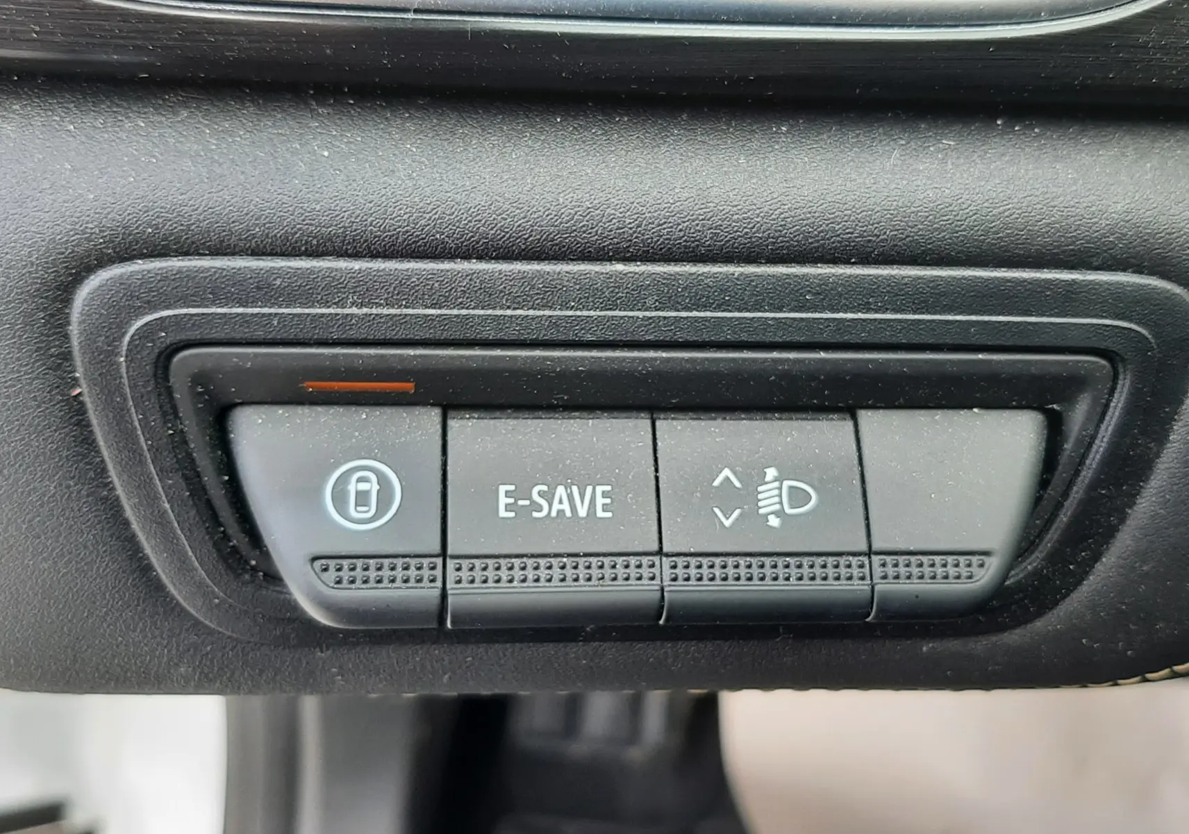 Boutons de commande du mode E-SAVE et réglage des phares dans l'habitacle noir du Renault Symbioz blanc nacré, vue rapprochée.