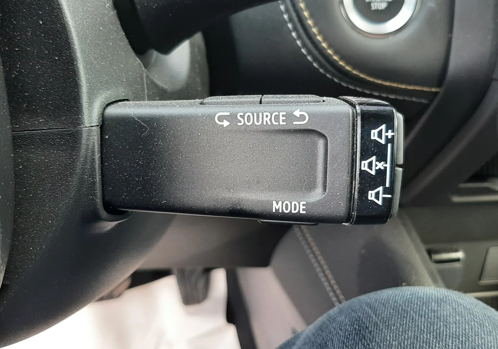 Gros plan sur la commande au volant gauche du Renault Symbioz blanc nacré, avec bouton source et mode visible.