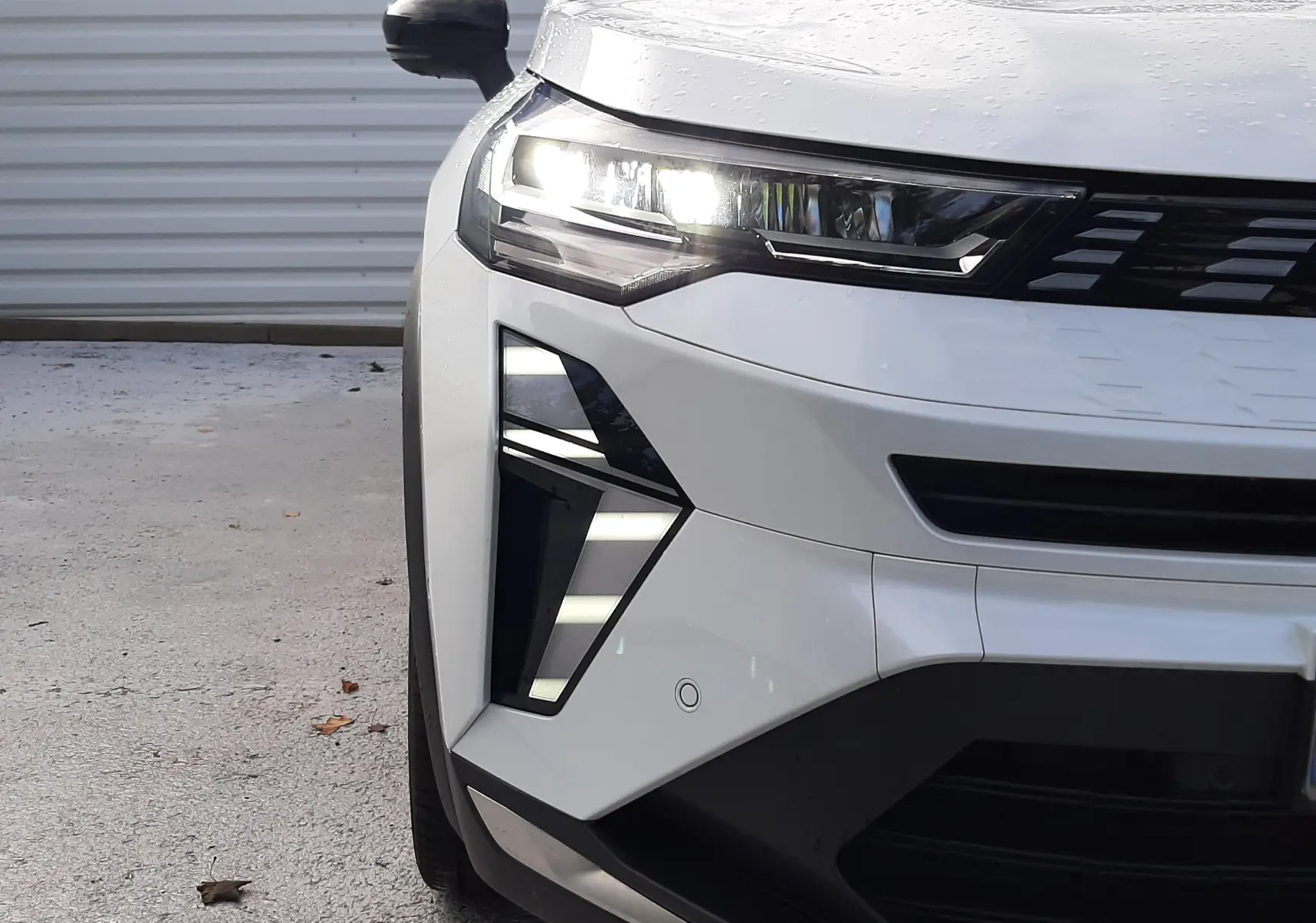 Vue avant gauche rapprochée du Renault SYMBIOZ blanc nacré, mettant en valeur ses phares LED et sa calandre moderne.