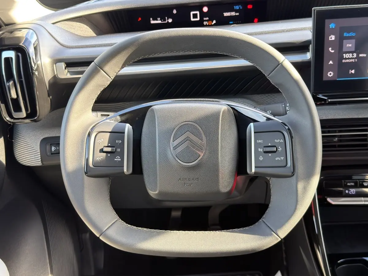 Vue rapprochée du volant cuir gris clair de la Citroën C3 2025 avec commandes multifonctions et tableau de bord numérique.