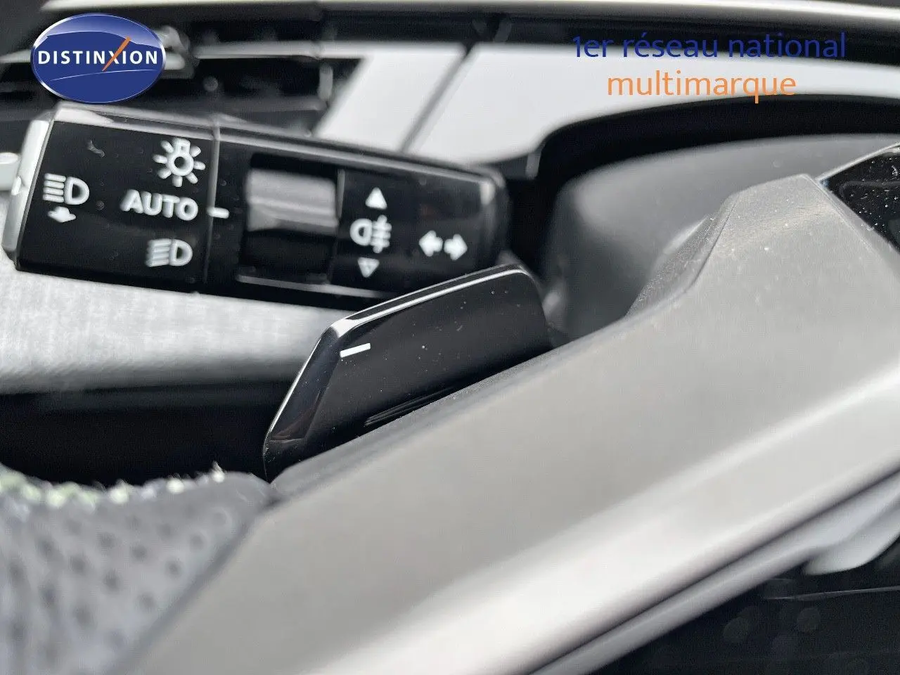 Gros plan sur la commande des feux et le levier de vitesses au volant du Peugeot 5008 Hybrid gris titane toit noir 2025.