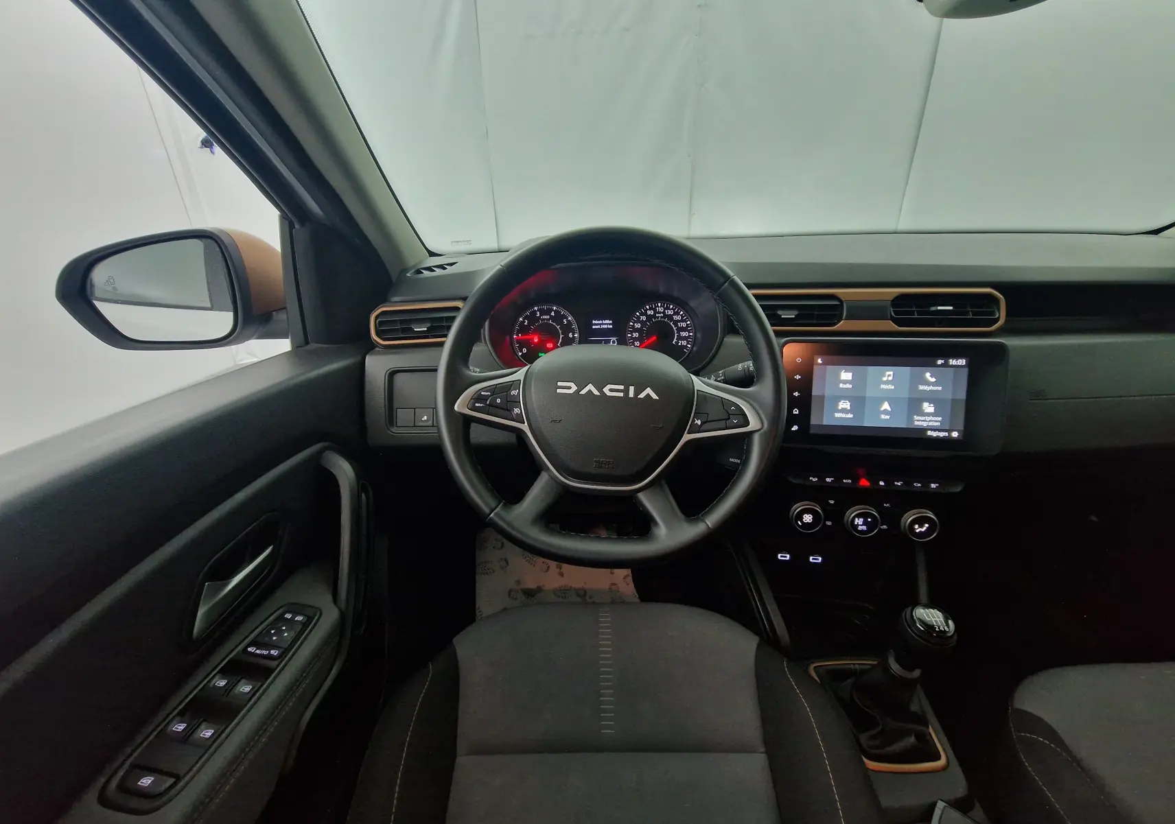 Vue intérieure centrée sur le volant noir DACIA et le tableau de bord avec écran tactile du Duster blanc 2024.