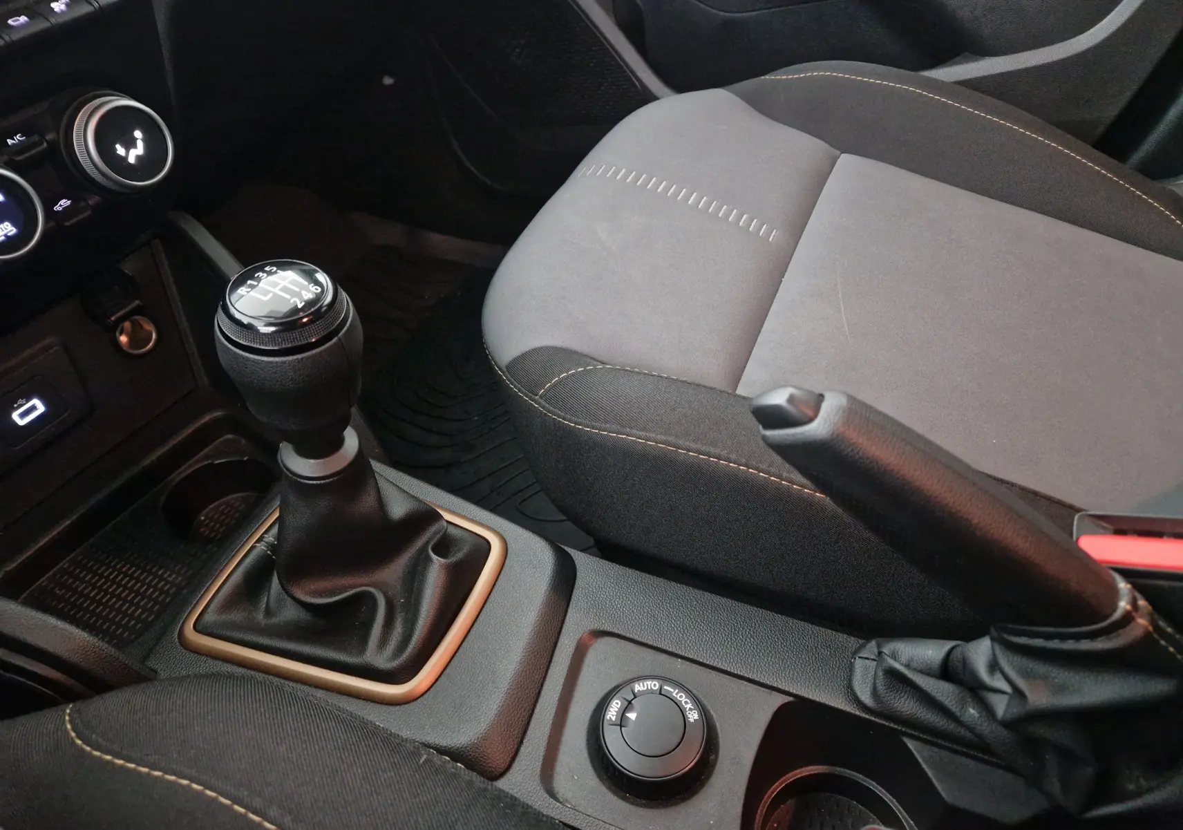 Gros plan intérieur sur la console centrale du Dacia Duster blanc 2024, avec levier de vitesses manuel et siège gris.