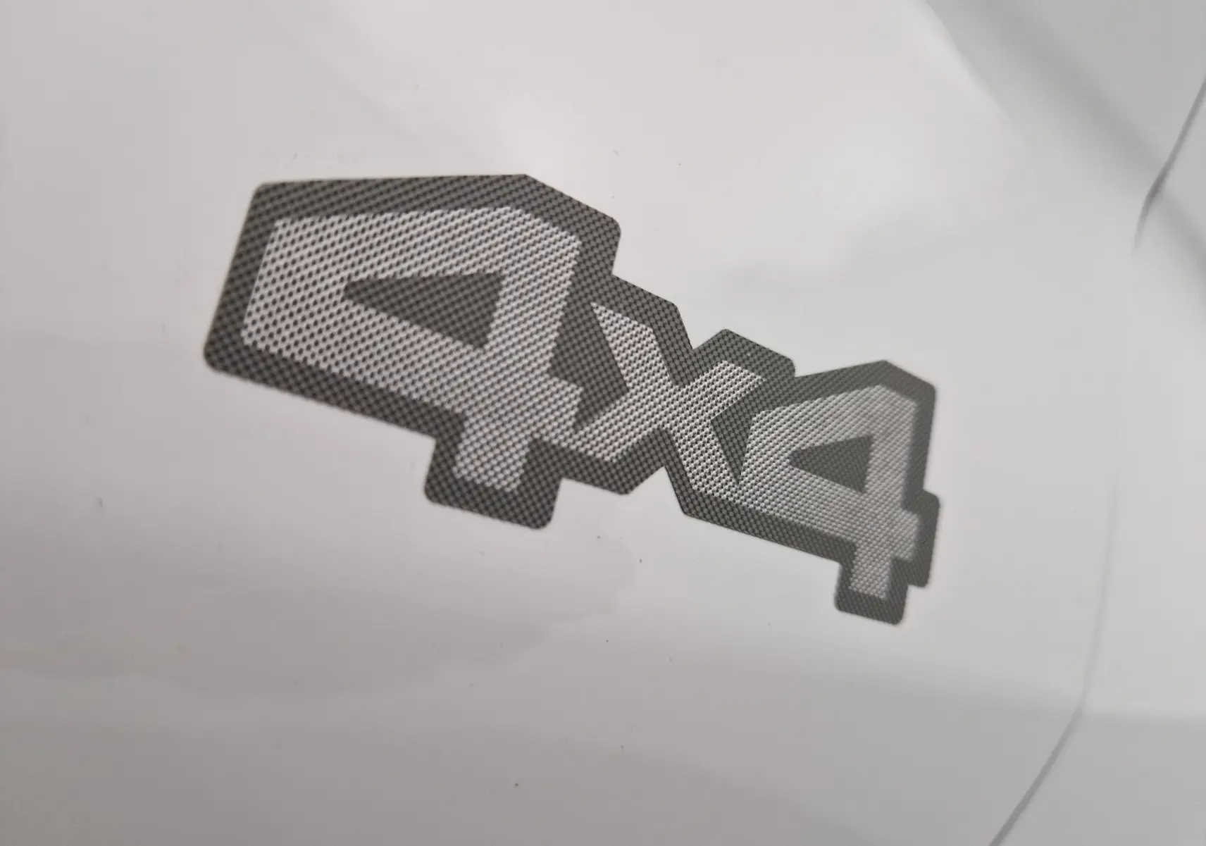 Gros plan sur l'autocollant 4x4 gris sur la carrosserie blanche du Dacia Duster 2024 version Extreme.