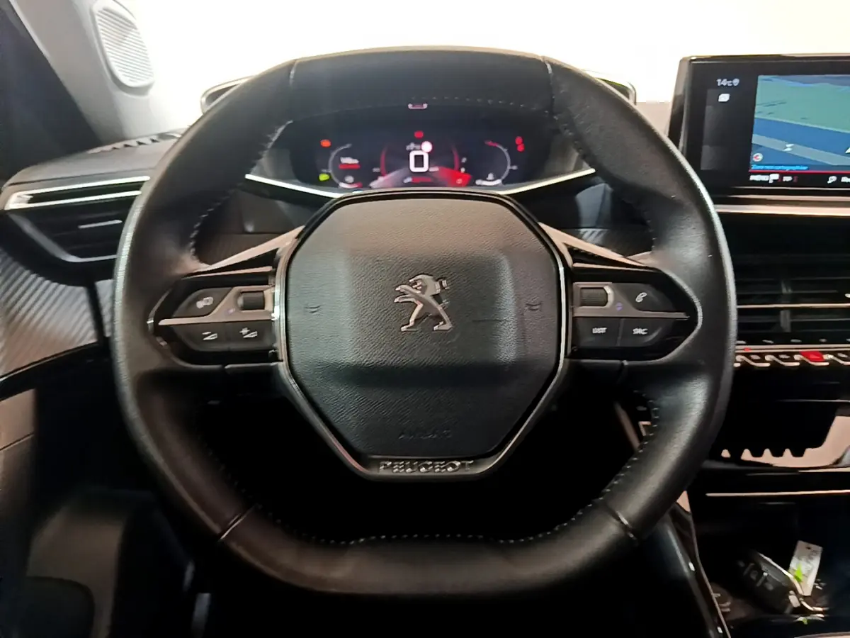 Volant cuir noir de Peugeot 2008 PureTech 130 2021 avec commandes intégrées et tableau de bord numérique en arrière-plan.