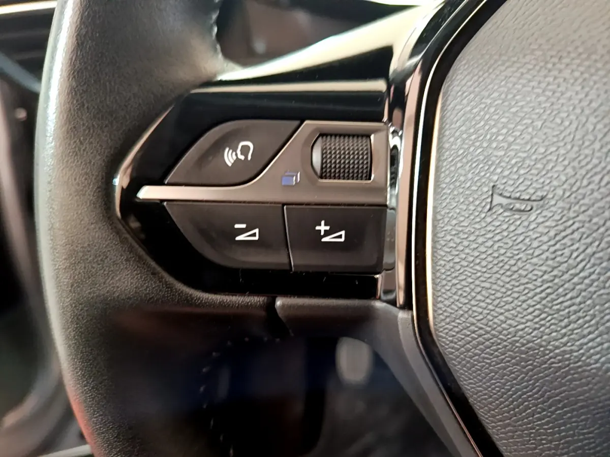 Gros plan sur les commandes gauche du volant cuir noir du Peugeot 2008 gris clair, version Allure Business 2021.