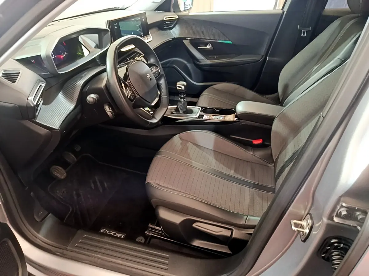 Intérieur avant droit du Peugeot 2008 gris clair 2021, volant cuir, tableau de bord numérique et boîte manuelle visible.