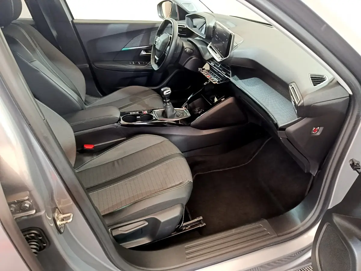 Intérieur côté conducteur d'une Peugeot 2008 gris clair, avec tableau de bord moderne et écran tactile central.