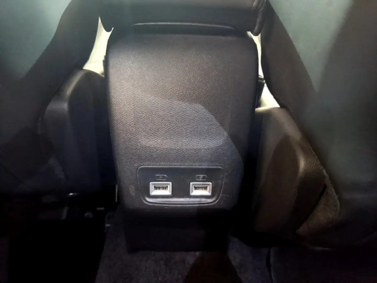 Vue rapprochée des ports USB arrière noirs entre les sièges arrière du Peugeot 2008 gris clair de 2021.