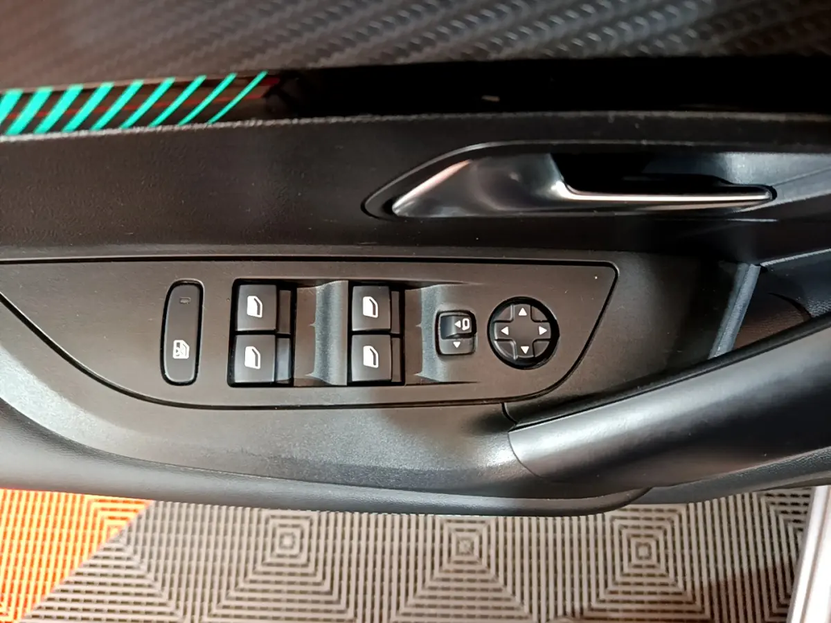 Panneau de porte côté conducteur du Peugeot 2008 gris clair, avec commandes électriques des vitres et rétroviseurs.