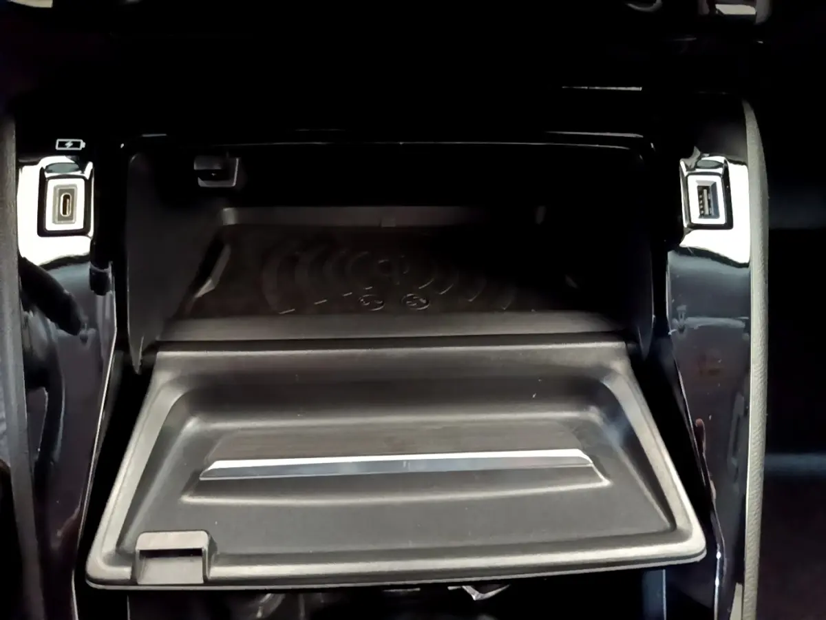 Vue rapprochée de la zone de recharge par induction et ports USB avant sur la console centrale noire du Peugeot 2008 gris clair.