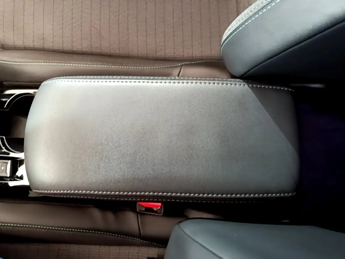 Vue rapprochée du couvercle de l'accoudoir central en cuir noir à surpiqûres dans l'habitacle du Peugeot 2008 gris clair.