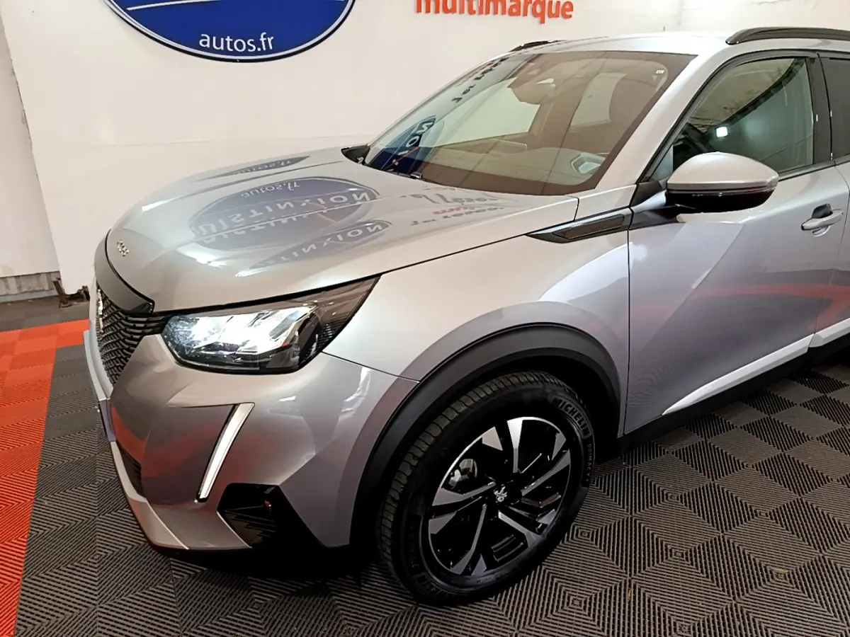 Peugeot 2008 gris clair vue 3/4 avant droit, mettant en valeur ses phares LED et jantes noires modernes.