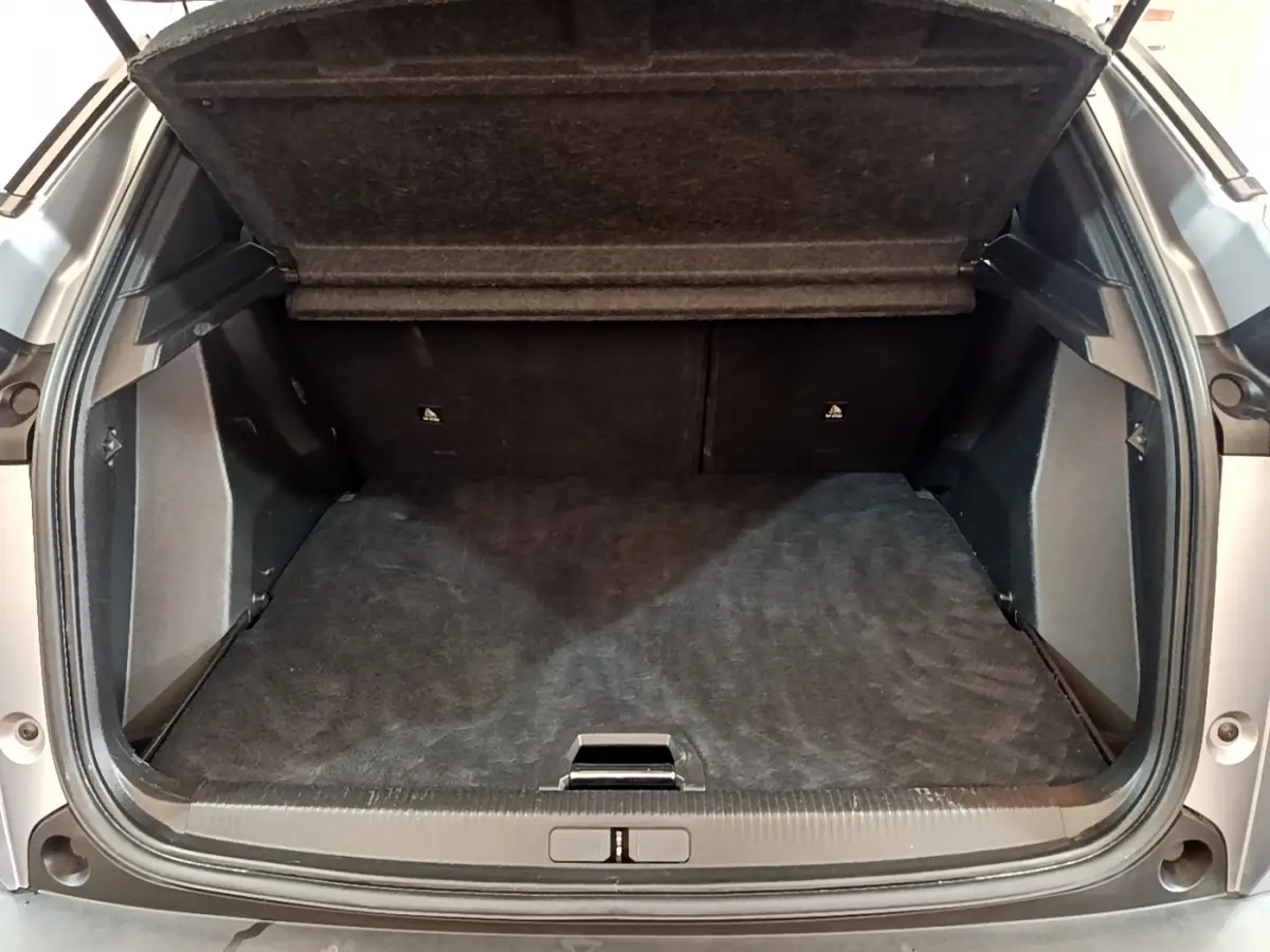 Coffre ouvert vu de l'arrière d'un Peugeot 2008 gris clair, montrant un espace de chargement propre et spacieux.