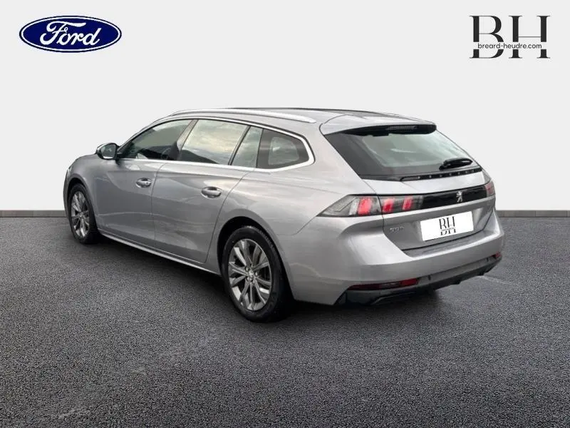 Peugeot 508 SW gris Platinium vue 3/4 arrière droit, avec barres de toit et feux arrière LED distinctifs.